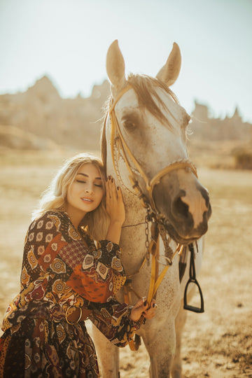 woman in black and white polka dot long sleeve shirt standing beside brown horse during daytime