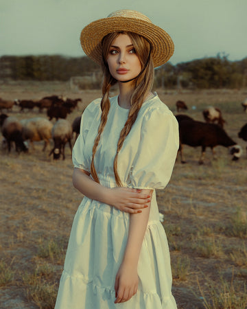 a woman in a straw hat standing in a field