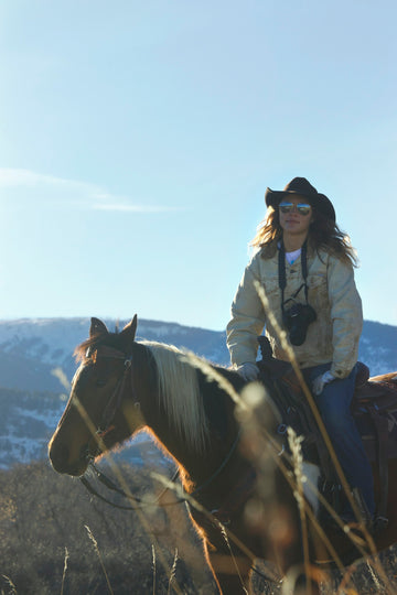 a woman riding on the back of a brown horse